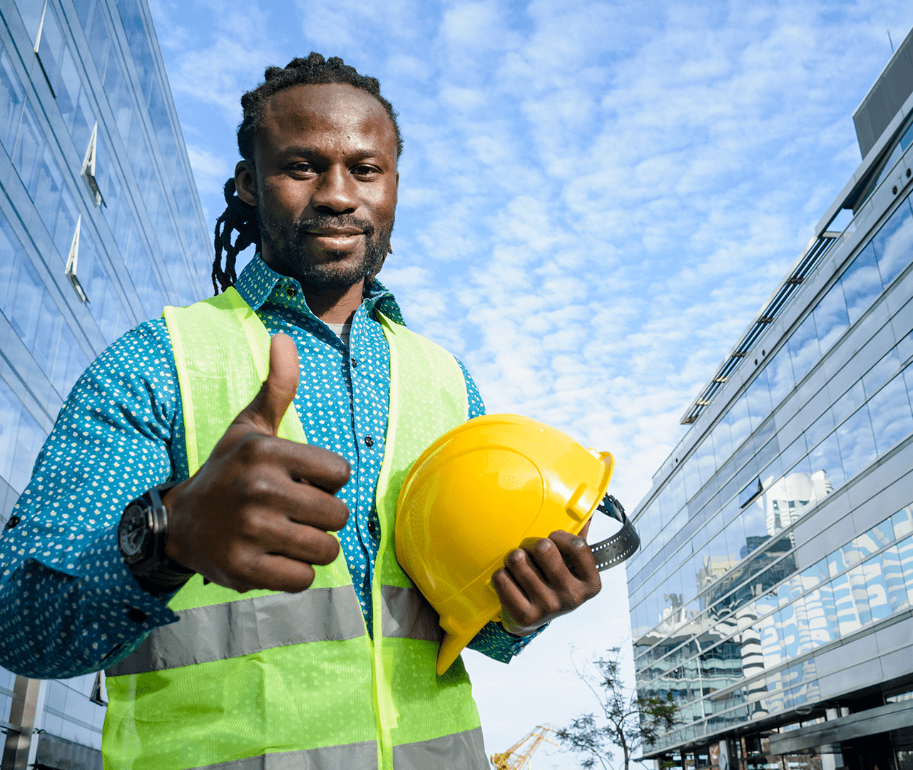 Homem com colete de obras segurando seu capacete.