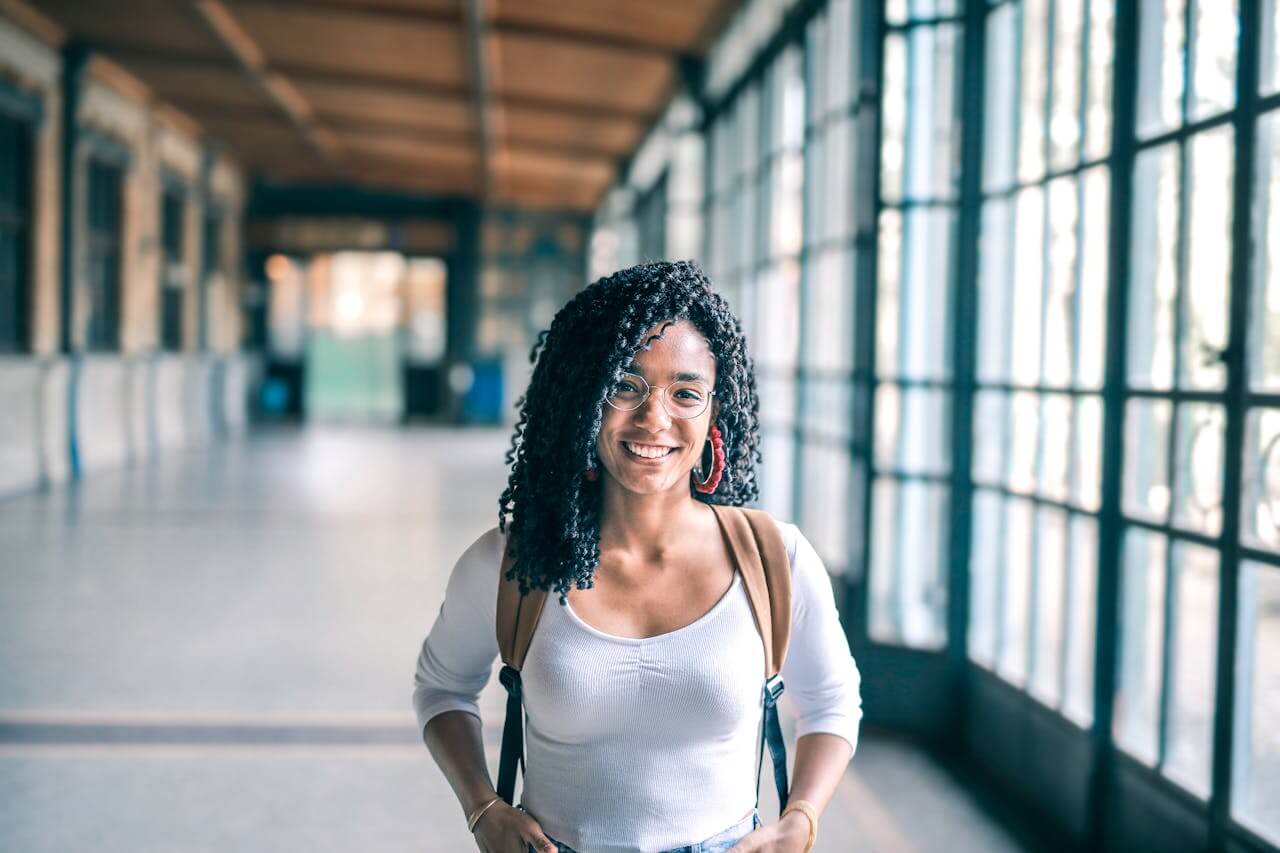 Menina estudante de mochila no corredor da faculdade.