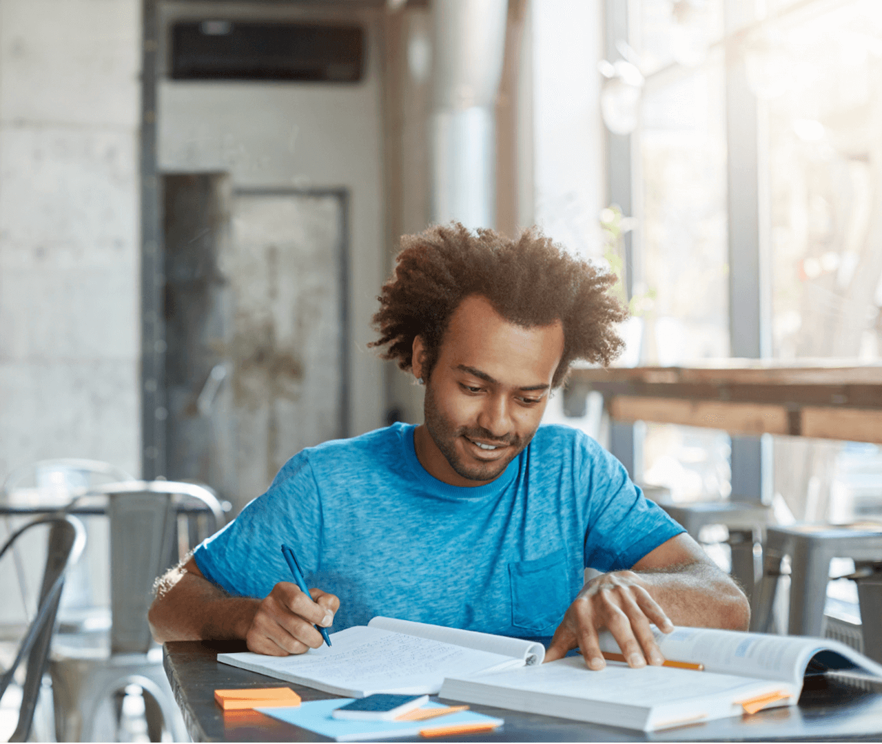 Homem estudando, fazendo anotações de um livro