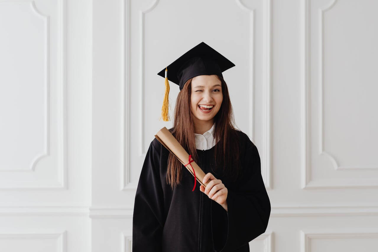 Menina feliz com toga segurando diploma universitário.