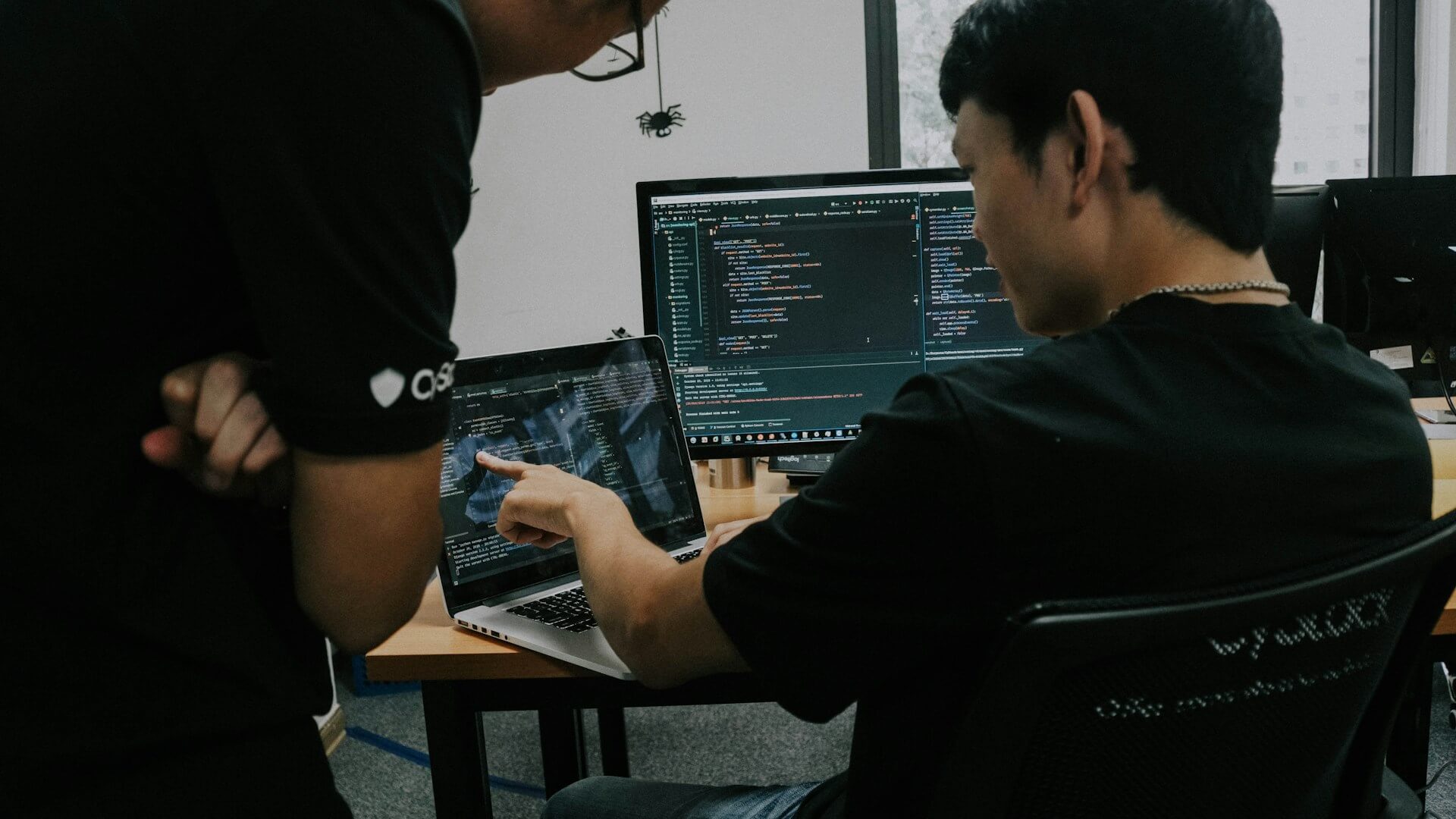 Homem programando em dois computadores.